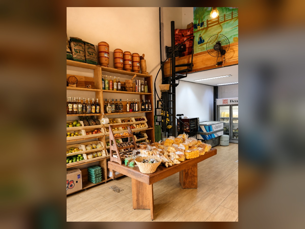 Visão geral do interior do Sítio do Vovô com prateleiras de madeira e mesa de quitandas